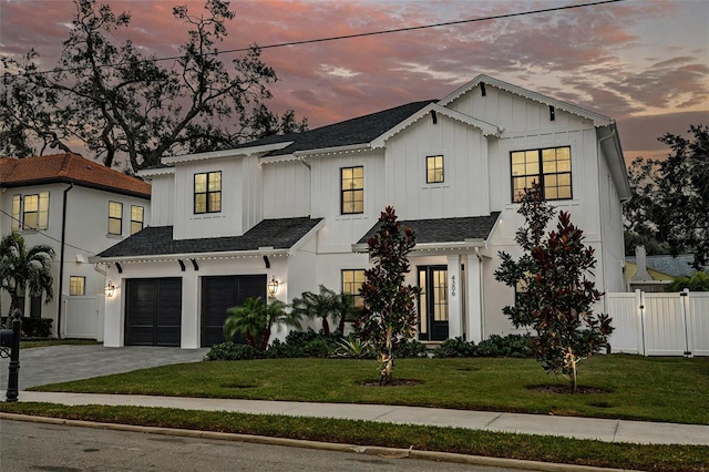 modern inspired farmhouse featuring a garage and a lawn