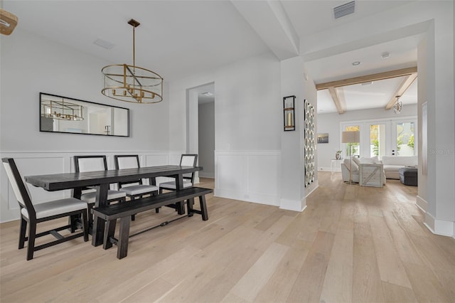 dining area featuring french doors, a notable chandelier, beamed ceiling, and light hardwood / wood-style floors