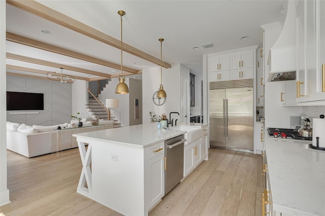 kitchen featuring decorative light fixtures, beamed ceiling, white cabinetry, a kitchen island with sink, and stainless steel appliances