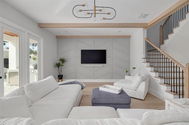 living room with beam ceiling, a chandelier, and light wood-type flooring