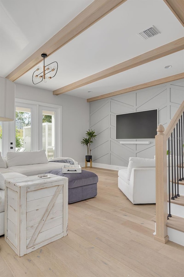 living room with a chandelier, light hardwood / wood-style floors, and beamed ceiling