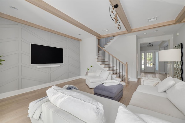 living room with french doors, beamed ceiling, and light hardwood / wood-style flooring