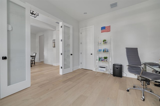 home office with light wood-type flooring and french doors