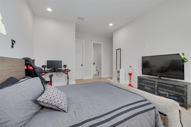 bedroom featuring connected bathroom and light hardwood / wood-style flooring