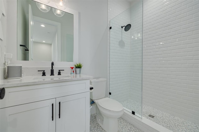 bathroom with toilet, vanity, tile patterned flooring, and a tile shower