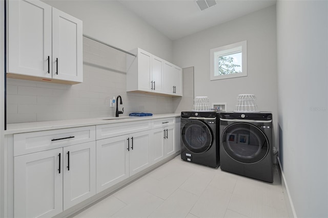 washroom with washing machine and dryer, cabinets, and sink