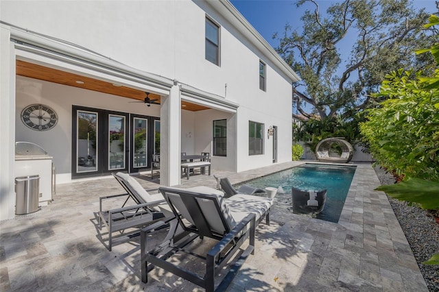 view of swimming pool with ceiling fan, a patio area, and an outdoor kitchen