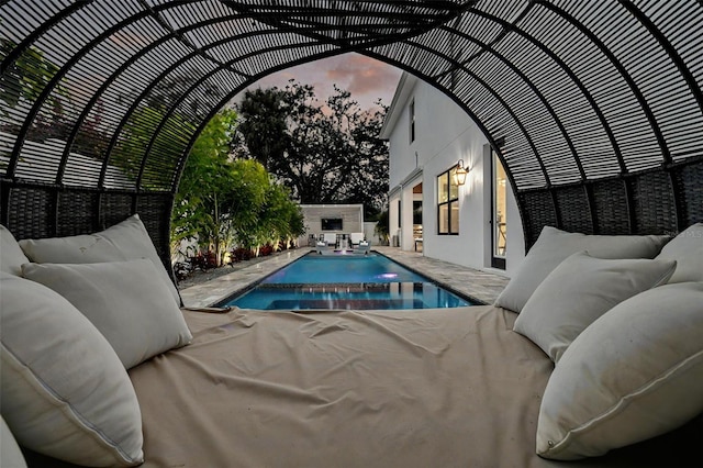 pool at dusk featuring a patio area