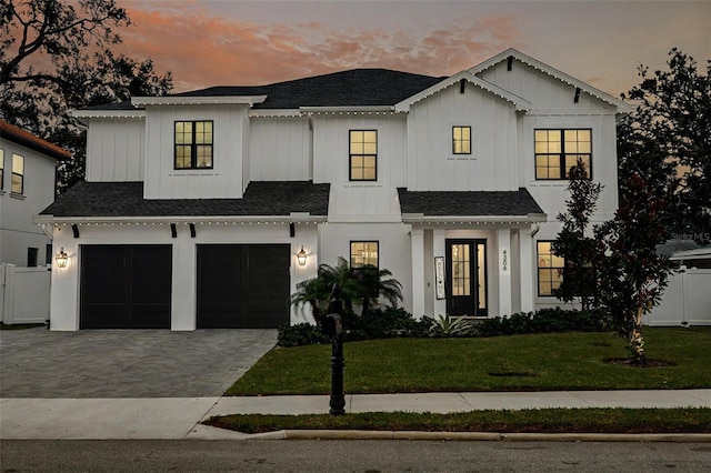 modern farmhouse featuring a garage and a lawn