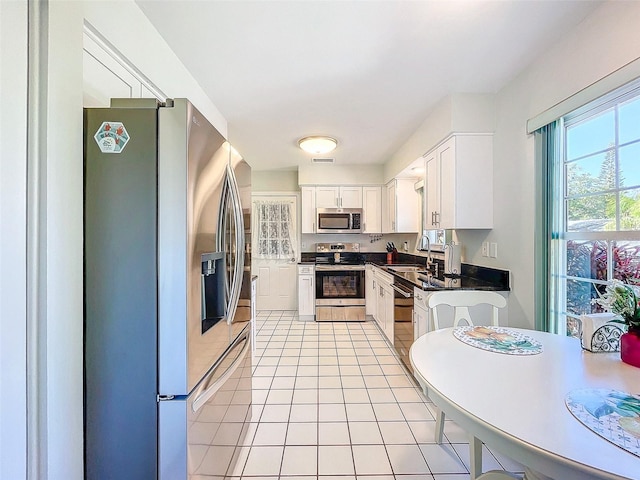 kitchen featuring sink, white cabinets, light tile patterned flooring, and appliances with stainless steel finishes