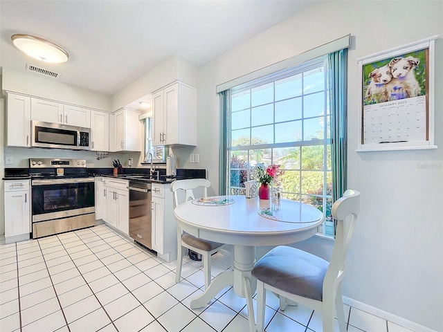 kitchen with light tile patterned floors, white cabinetry, sink, and appliances with stainless steel finishes