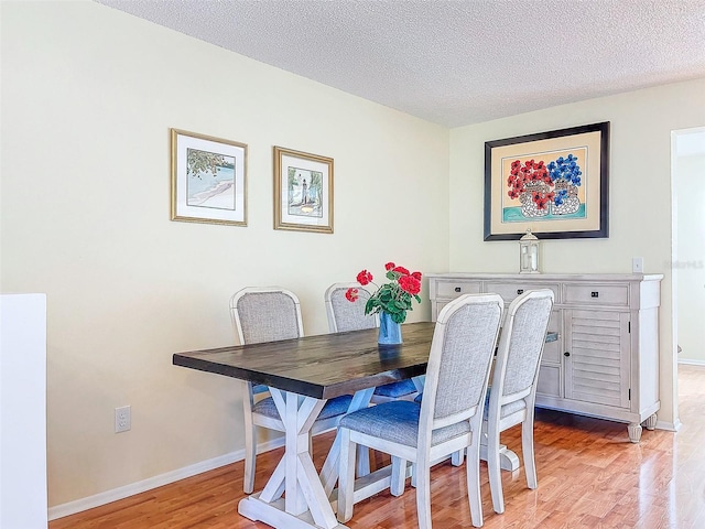 dining area featuring a textured ceiling and light hardwood / wood-style floors