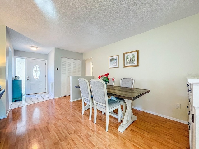 dining area with a textured ceiling and light hardwood / wood-style floors