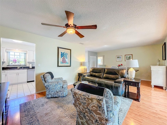 living room featuring a textured ceiling, light wood-type flooring, and ceiling fan