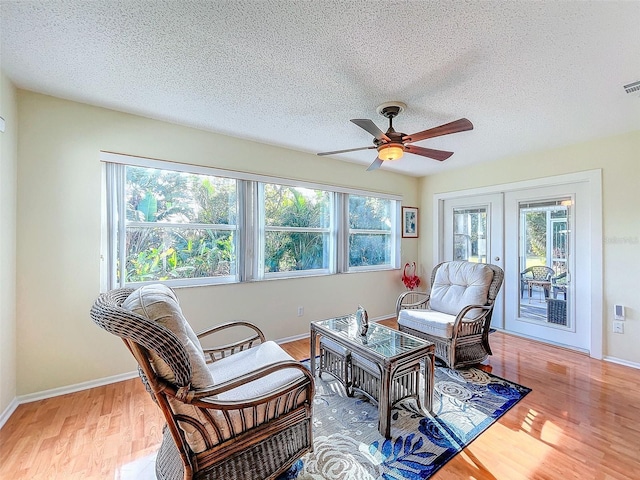 sitting room featuring french doors, a textured ceiling, hardwood / wood-style flooring, and ceiling fan