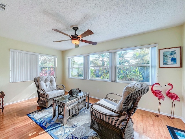 sitting room featuring ceiling fan, a textured ceiling, and light wood-type flooring