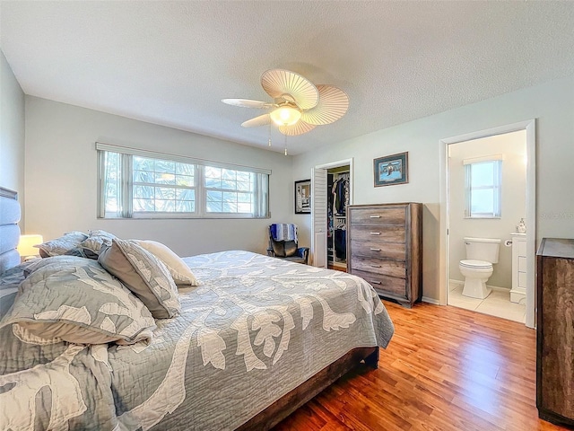 bedroom featuring a walk in closet, ensuite bath, ceiling fan, light hardwood / wood-style floors, and a closet