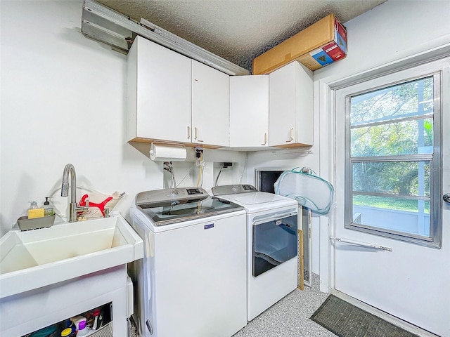 clothes washing area featuring sink, washer and dryer, cabinets, and a textured ceiling