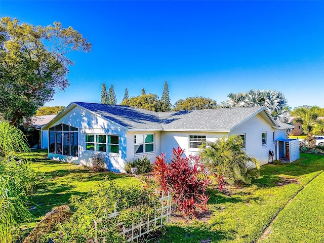 back of house featuring a sunroom and a lawn