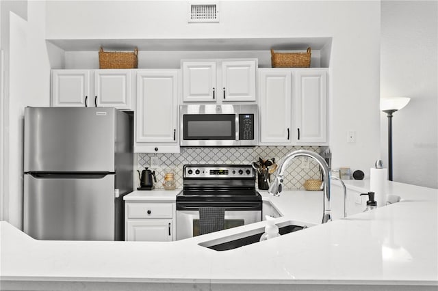 kitchen with white cabinets, decorative backsplash, light stone counters, and stainless steel appliances