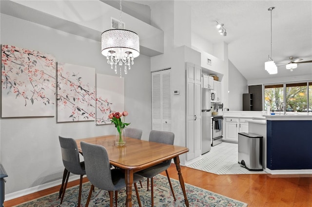 dining area featuring a towering ceiling, light wood-type flooring, and a notable chandelier