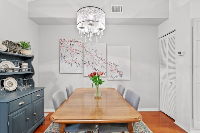 dining space with hardwood / wood-style floors and a notable chandelier