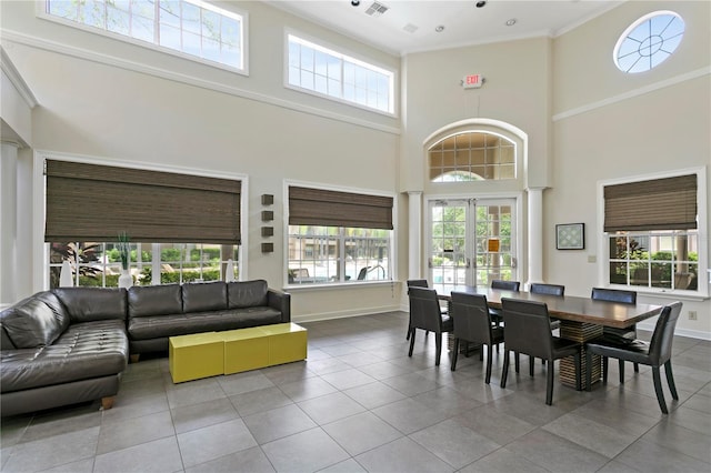 dining room with tile patterned floors, crown molding, and a high ceiling