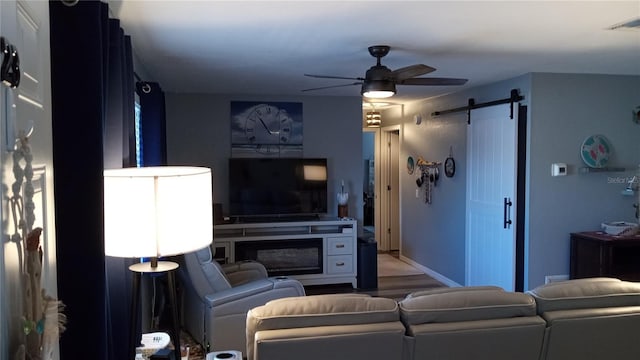 living room featuring ceiling fan and a barn door