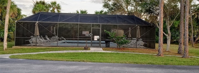 rear view of house with a lawn, a patio, and a lanai