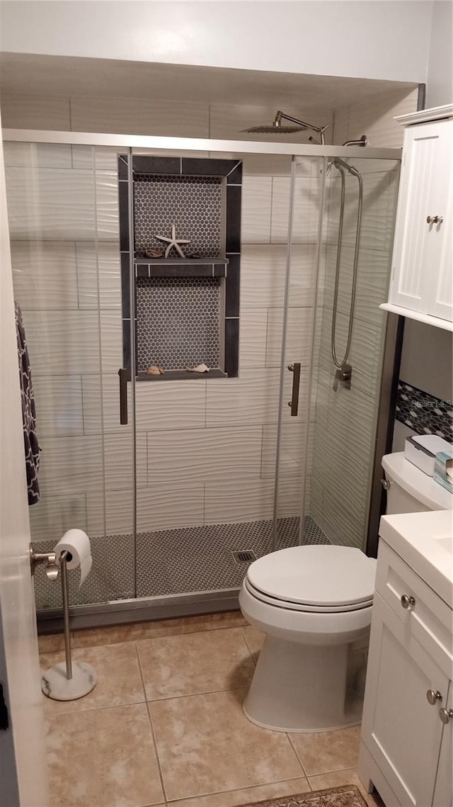 bathroom with tile patterned flooring, vanity, a shower with door, and toilet