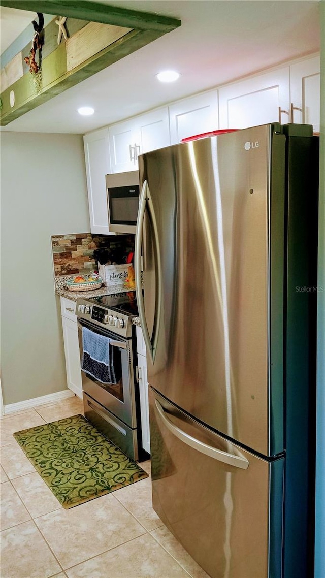 kitchen with white cabinets, light tile patterned flooring, backsplash, and appliances with stainless steel finishes