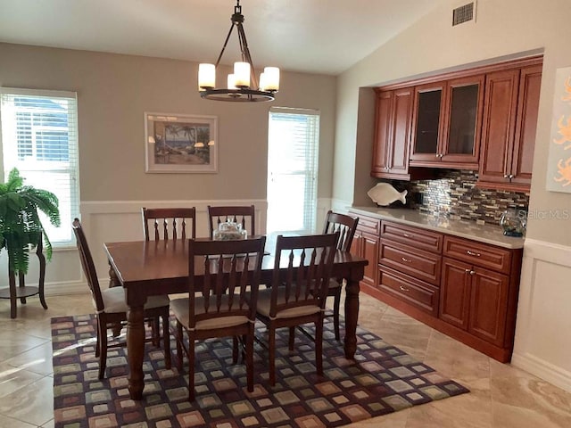 dining space with lofted ceiling, an inviting chandelier, light tile patterned floors, and a wealth of natural light