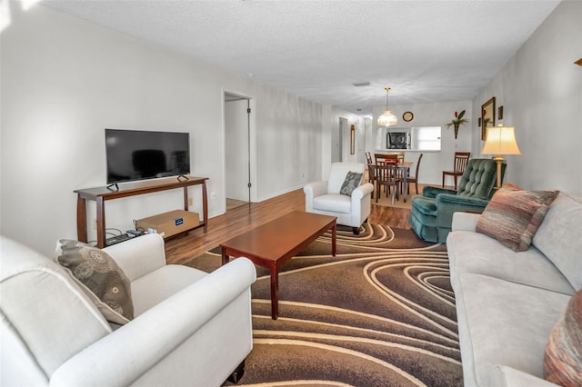 living room with hardwood / wood-style floors, a textured ceiling, and an inviting chandelier