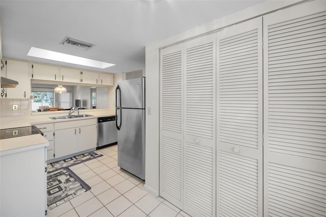 kitchen featuring sink, cream cabinets, extractor fan, light tile patterned flooring, and appliances with stainless steel finishes