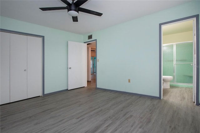 unfurnished bedroom with hardwood / wood-style floors, a closet, ensuite bathroom, and ceiling fan