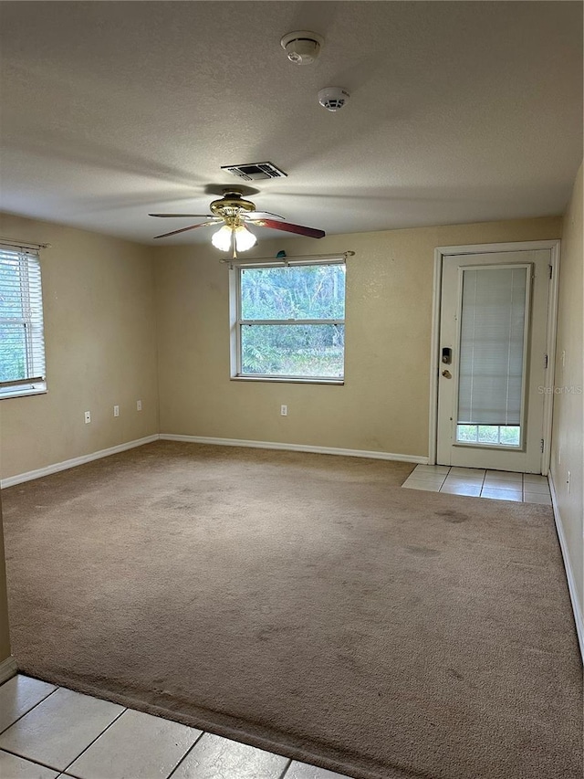 unfurnished room featuring ceiling fan, light tile patterned floors, and a textured ceiling