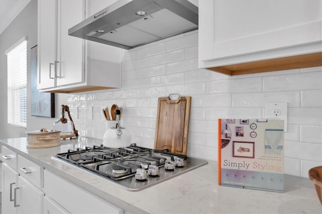 kitchen with light stone countertops, tasteful backsplash, stainless steel gas cooktop, exhaust hood, and white cabinets