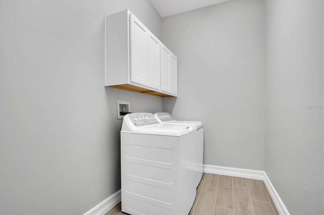 clothes washing area featuring cabinets, independent washer and dryer, and light hardwood / wood-style flooring