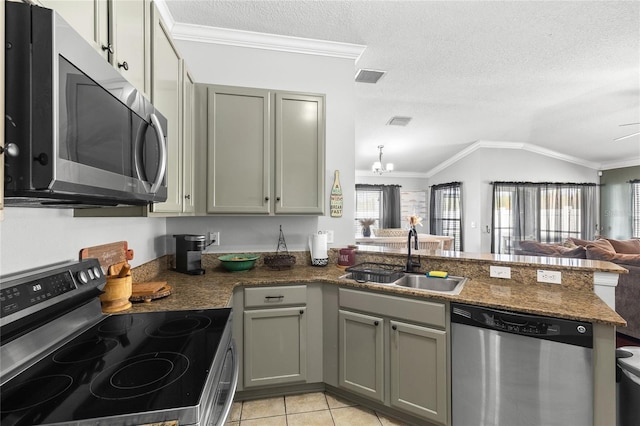 kitchen with sink, vaulted ceiling, a textured ceiling, appliances with stainless steel finishes, and light tile patterned flooring