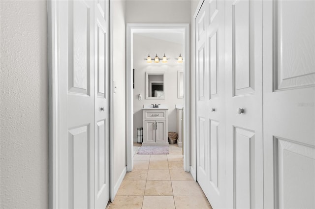 hall featuring sink and light tile patterned floors