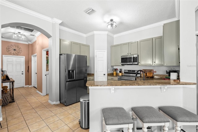 kitchen with kitchen peninsula, appliances with stainless steel finishes, dark stone counters, a textured ceiling, and light tile patterned floors