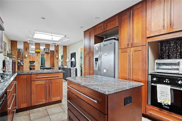 kitchen with light stone countertops, appliances with stainless steel finishes, a center island, and light tile patterned flooring