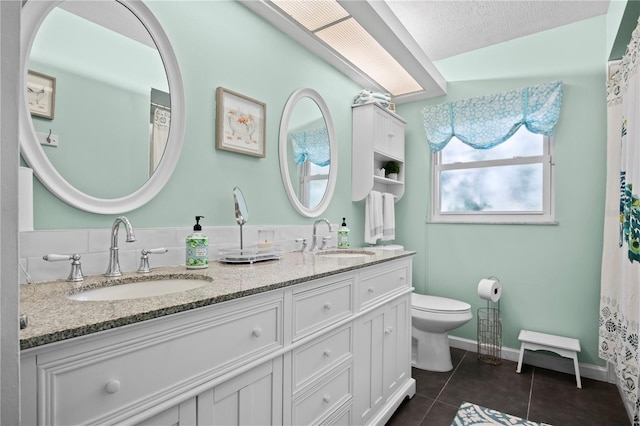 bathroom featuring tile patterned floors, vanity, toilet, and a textured ceiling