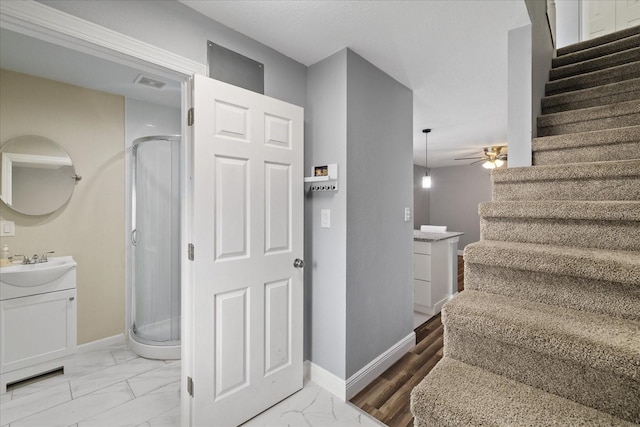 staircase with ceiling fan and sink