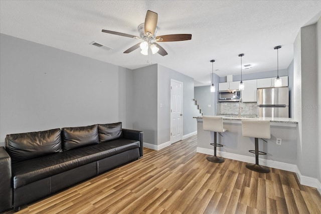 living room with hardwood / wood-style floors, a textured ceiling, ceiling fan, and sink