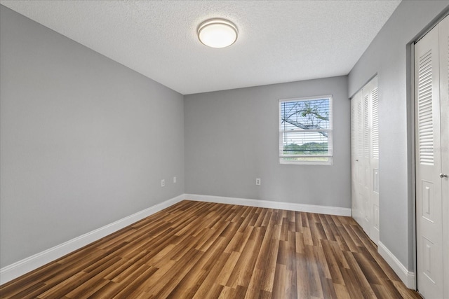 unfurnished bedroom featuring dark hardwood / wood-style flooring and a textured ceiling