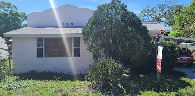 509 Rosery Rd NW, Largo, FL 33770 - view of property exterior with stucco siding, an attached carport, roof with shingles, and fence