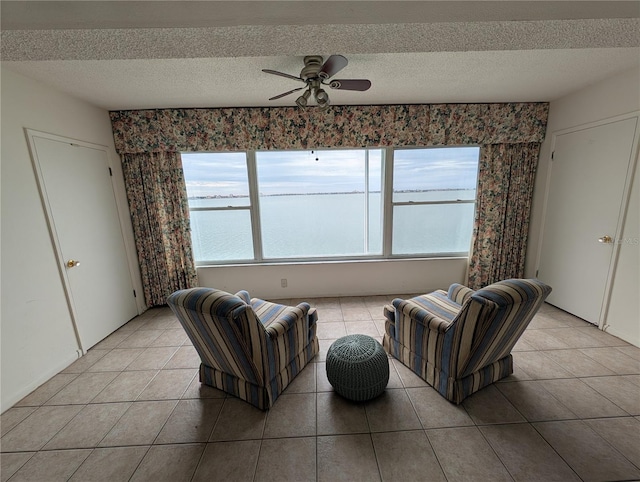 living room featuring a textured ceiling, ceiling fan, and light tile patterned flooring