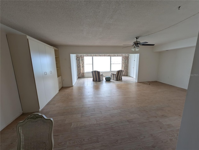 unfurnished room featuring ceiling fan, light wood-type flooring, and a textured ceiling