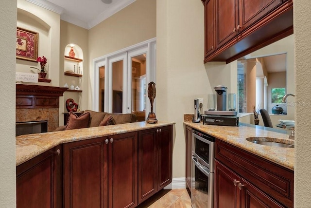 kitchen featuring built in shelves, light stone counters, kitchen peninsula, and sink